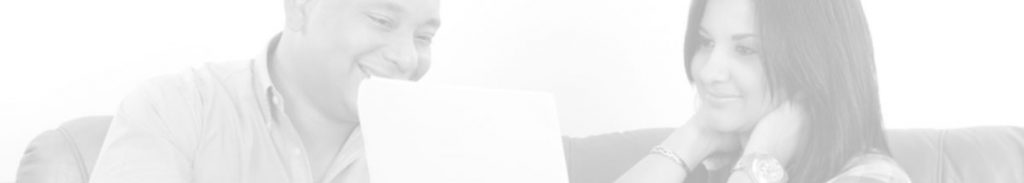 Black and white image of a man and women looking at a laptop computer and smiling
