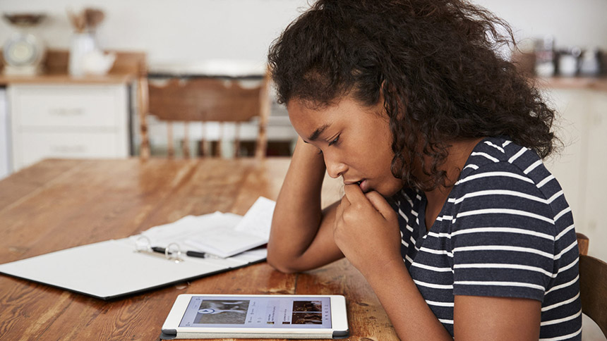 A woman looking at her iPad very sad because her digital reputation is ruined because of cyberbullying.