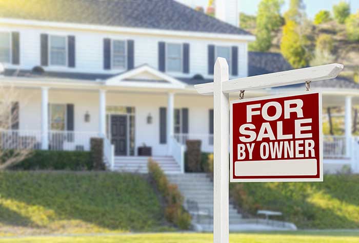 A home with a sign in the yard that says "For sale by owner."