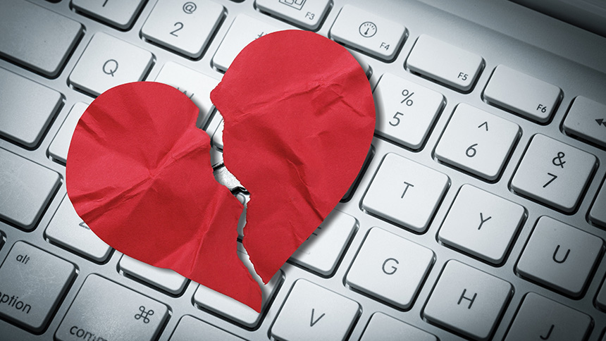 A crumpled up broken paper heart on top of a computer keyboard, signifying a Romance Scam.