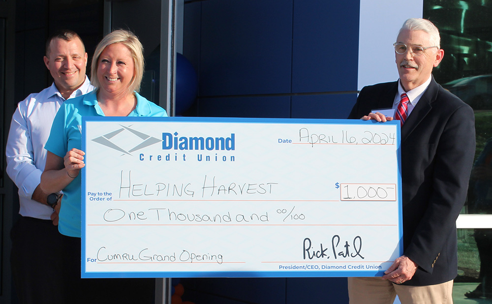 A giant check for $1,000 being presented to Helping Harvest for the Cumru branch's grand opening.