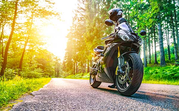 A motorcycle parked along a back road in the woods.