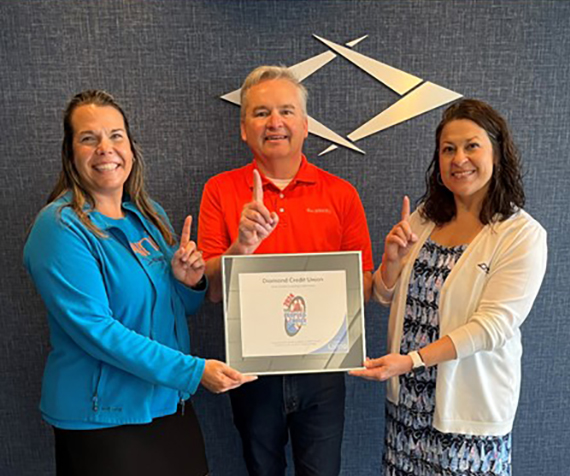 Three Diamond employees hold up one finger to show they won the People's Choice award for 2024.