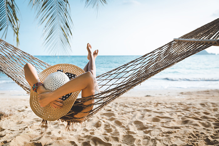 A woman relaxing in a hammock at the beach.