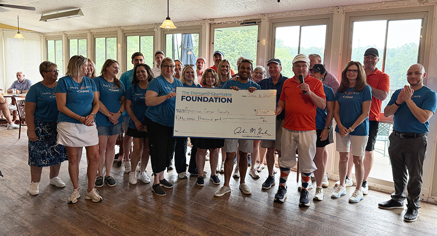 A group of 24 Diamond Credit Union employees are pictured in the upstairs screen in porch at Golden Oaks Golf Club in Fleetwood. In the middle, three employees are holding a large check from The Diamond Charitable Foundation. It is addressed to the American Cancer Society for $57,000.