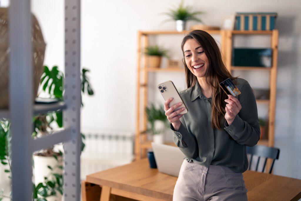 Happy woman holding phone and credit card for Loans and Credit page.