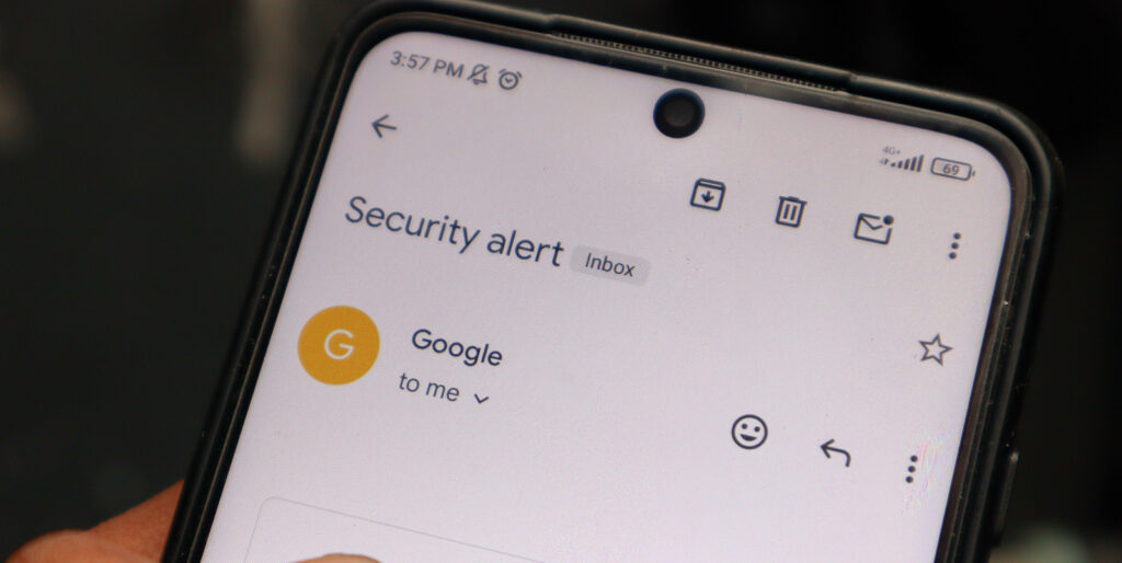 Receiving a security alert email on a smartphone, signifying the beginning of account takeover fraud.