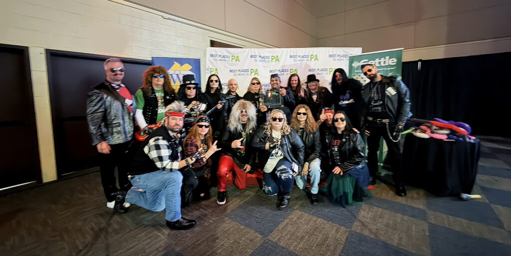 Diamond Credit Union employees and board members are pictured in a group photo at the Best Places to Work award ceremony. They are dressed in 80s rock costumes.