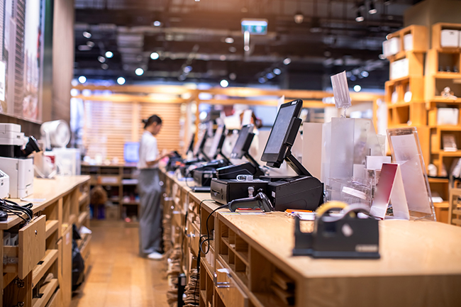 A picture behind the row of cash registers in a department store with a cashier standing at the last register, to help symbolize department store credit cards.