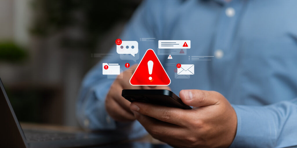 Man holding phone with phishing alerts appearing.