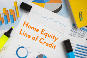 financial document that says, "Home Equity Line of Credit" surrounded by highlighters and a financial paper with a pie chart.