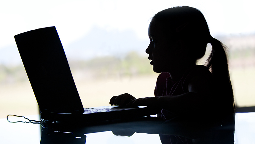 Help your children stay safe online: This is an image on young girl looking at a laptop screen. It's a side profile and she is silhouetted so you don't see details.