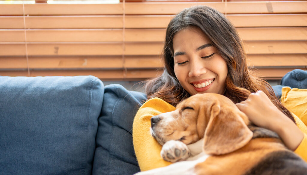 A first-time pet owner holding her dog on a couch.