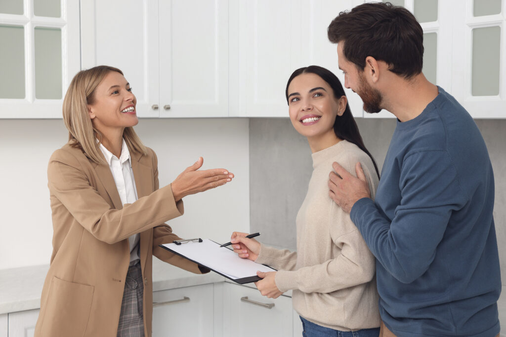 Female realtor talking to a couple who is signing a contract, illustrating the benefits of using a realtor.