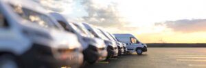 row of business vans parked in a lot. the van at the end of the row is sticking out as the focal point. represents business vehicle loans.