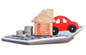 calculator with a stack of coins, wooden house, and red car on top.