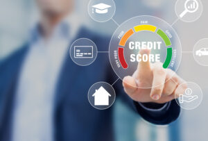 man in a suit pointing forward to an image of a wheel with red, orange, yellow, light green, and dark green to represent bad to excellent credit. The middle of the wheel says "credit score" and there are images of a house, graduation cap, credit card, magnifying glass, car and hand with dollar sign around the wheel. 