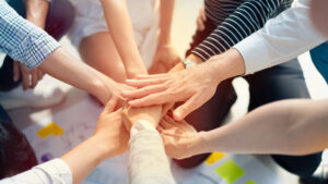 group of people placing their hands on top of eachothers.