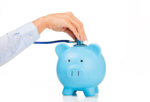 Blue piggy bank with a person's hand holding a stethoscope on it.